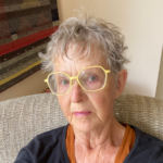 A headshot photograph of Wendy Bertrand. She has short blonde hair and is wearing bright yellow glasses.